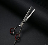 Professional hair thinning scissors with red finger rings on black textured background