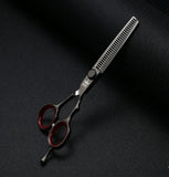 Professional hair thinning scissors with red finger rings on black textured background