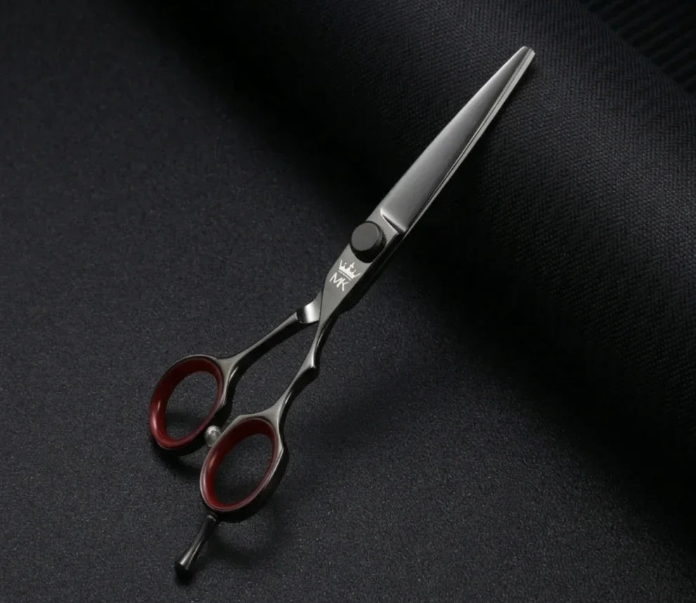 Professional hair cutting scissors with red finger rings on a dark textured background